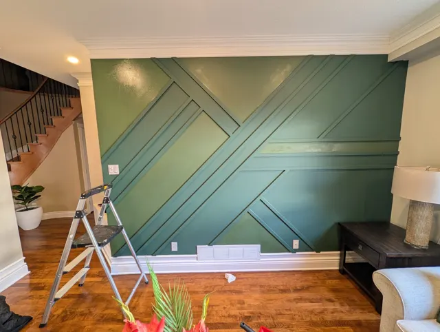 Green geometric wall on install day, a step ladder still in front of it