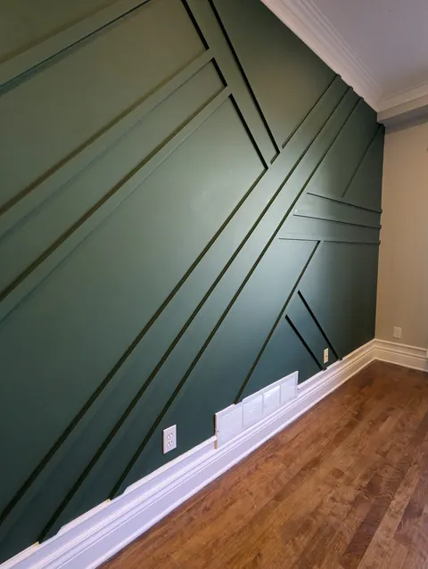 Green geometric accent wall with crossing battens, seen at an angle