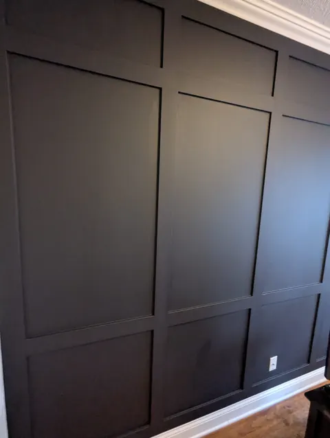 Floor-to-ceiling grid panel wall painted near black