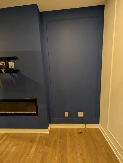 Navy panelled TV wall with an electric fireplace set into it